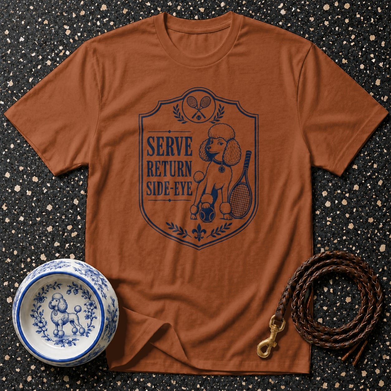 Brown t-shirt with blue poodle graphic, tennis rackets, and text "Serve Return Side-Eye".