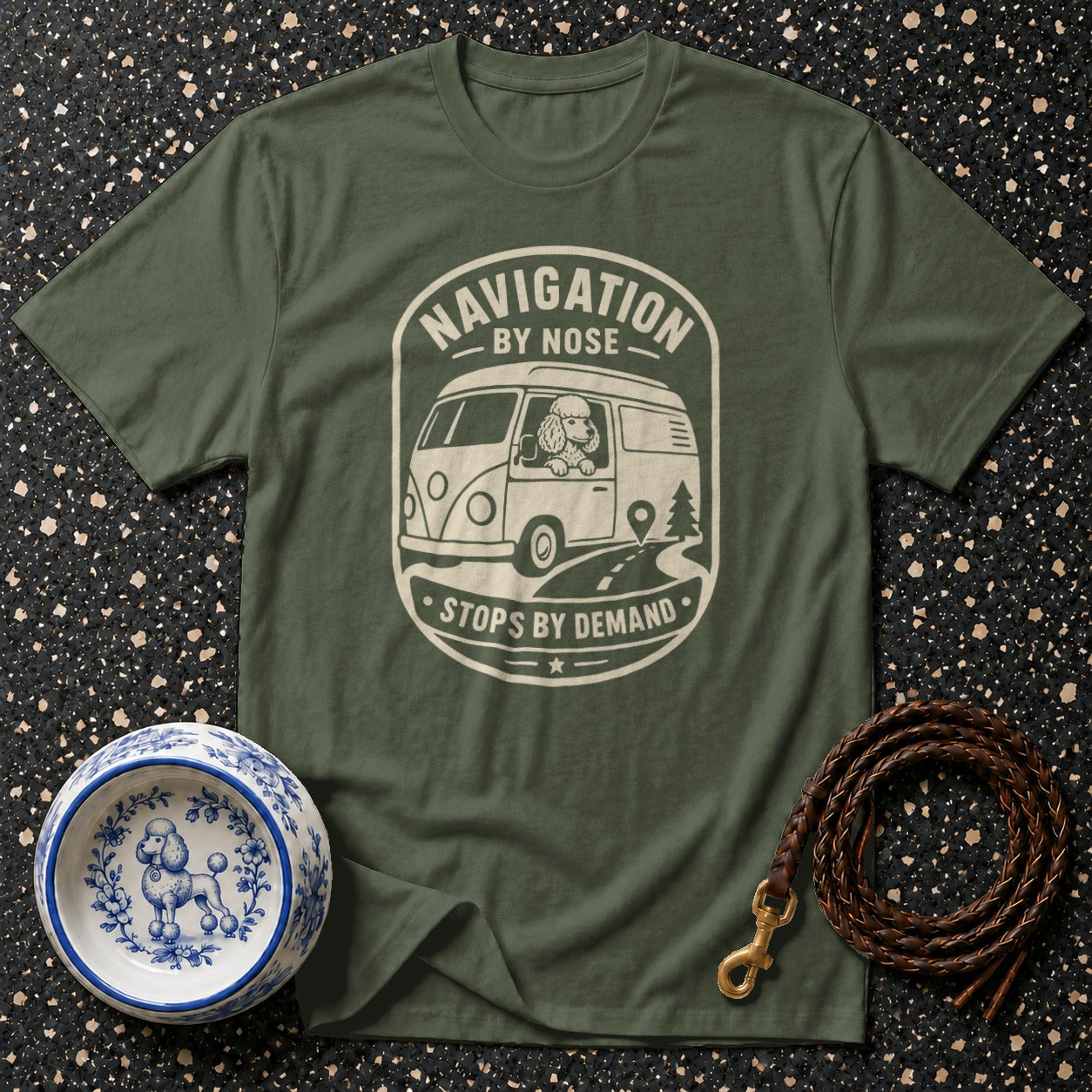 Green t-shirt with a print of a poodle in a van reading "Navigation by Nose, Stops by Demand."