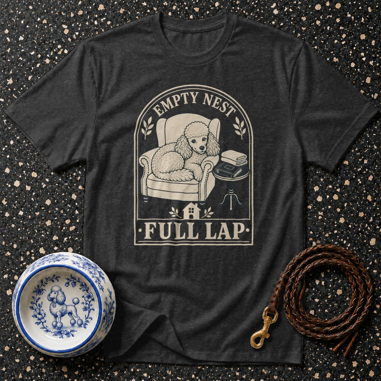 Dark t-shirt with poodle in armchair graphic, reads "Empty Nest Full Lap".