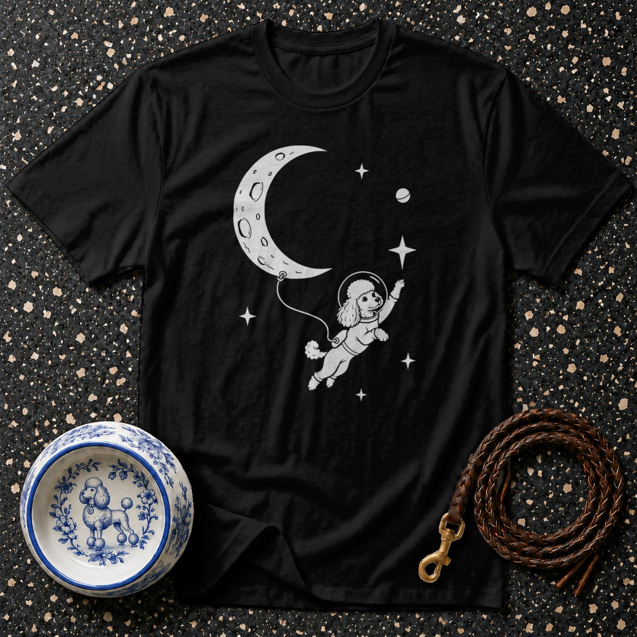 Black t-shirt with a poodle astronaut floating near a crescent moon and stars.