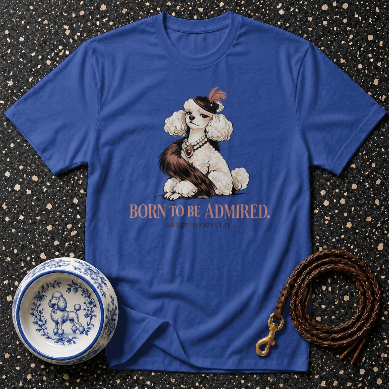 Blue t-shirt with a white poodle wearing a hat and pearls, and text "BORN TO BE ADMIRED."