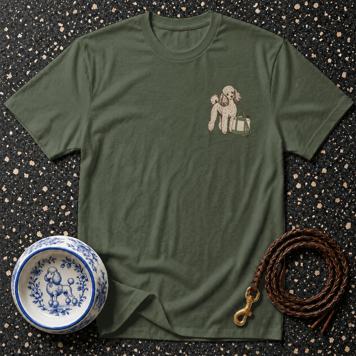 Green t-shirt with a small poodle and bag embroidery, shown with a patterned dog bowl and leash.