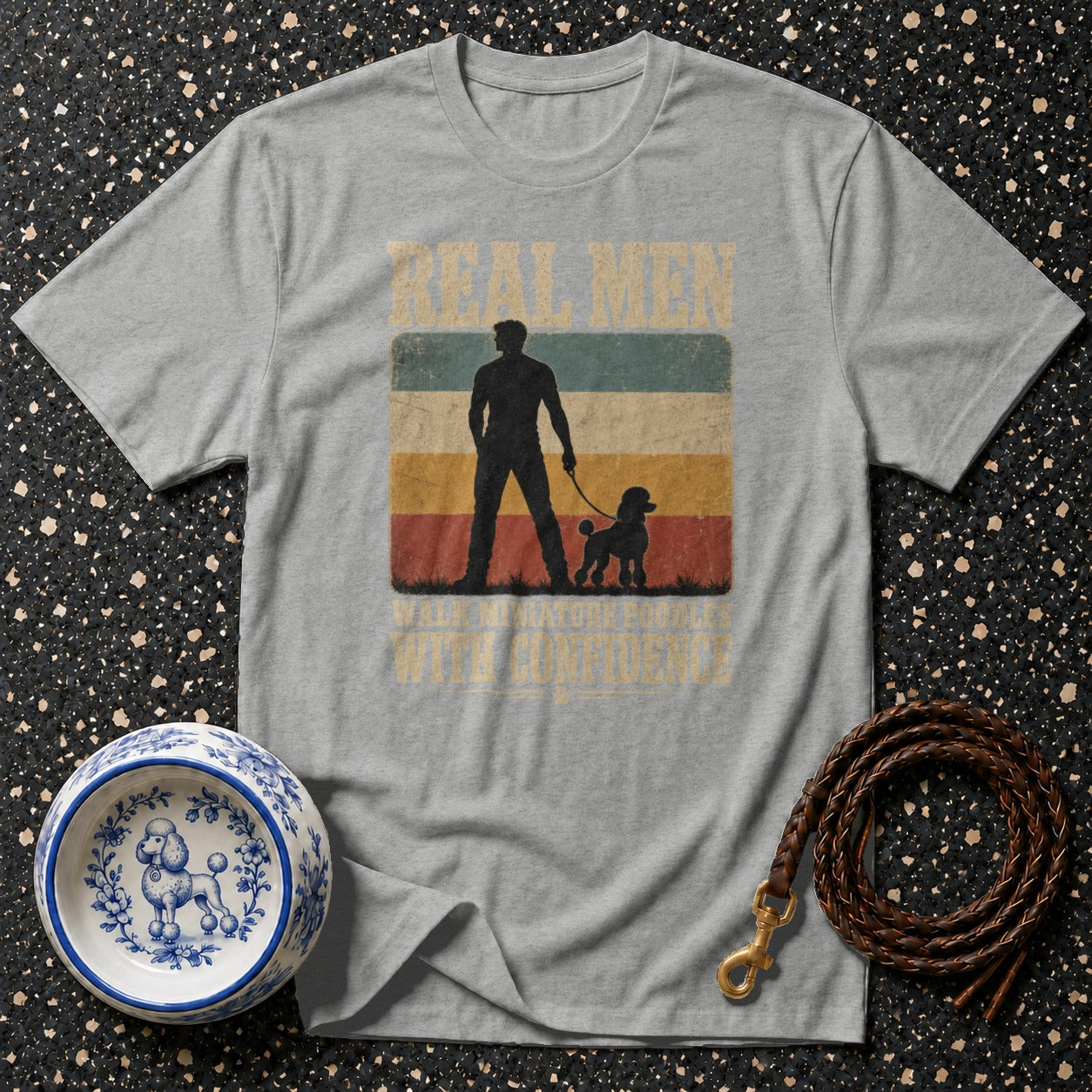 Grey t-shirt with a graphic of a man and poodle, reads "Real Men Walk Poodles with Confidence."