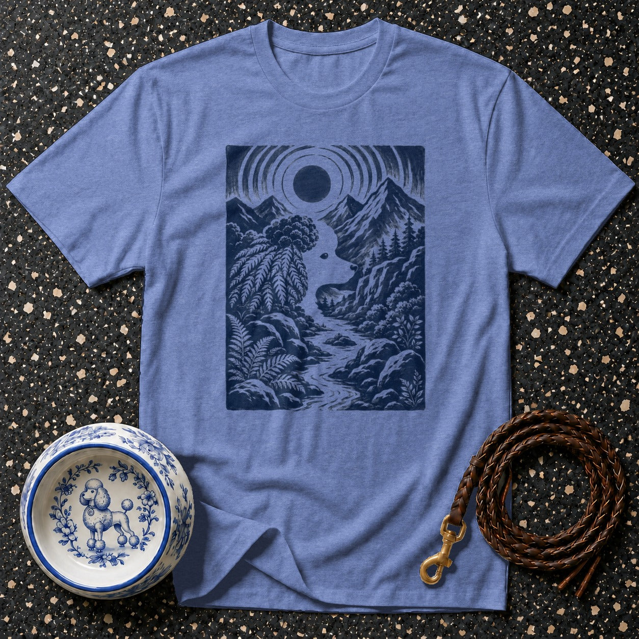 Blue t-shirt with a dark blue nature scene print, pet bowl, and leash.