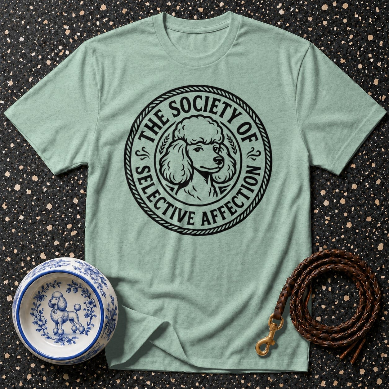 Light green t-shirt with black poodle graphic and text, dog bowl, and coiled leash.