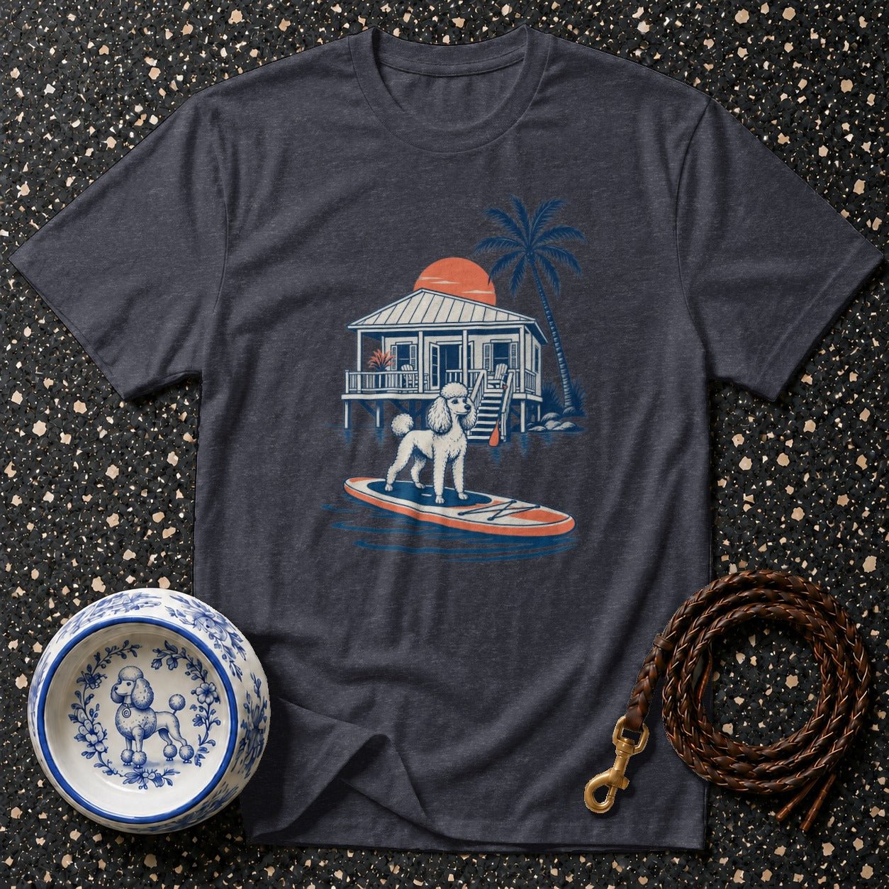 T-shirt with a white poodle on a paddleboard in front of a beach house.