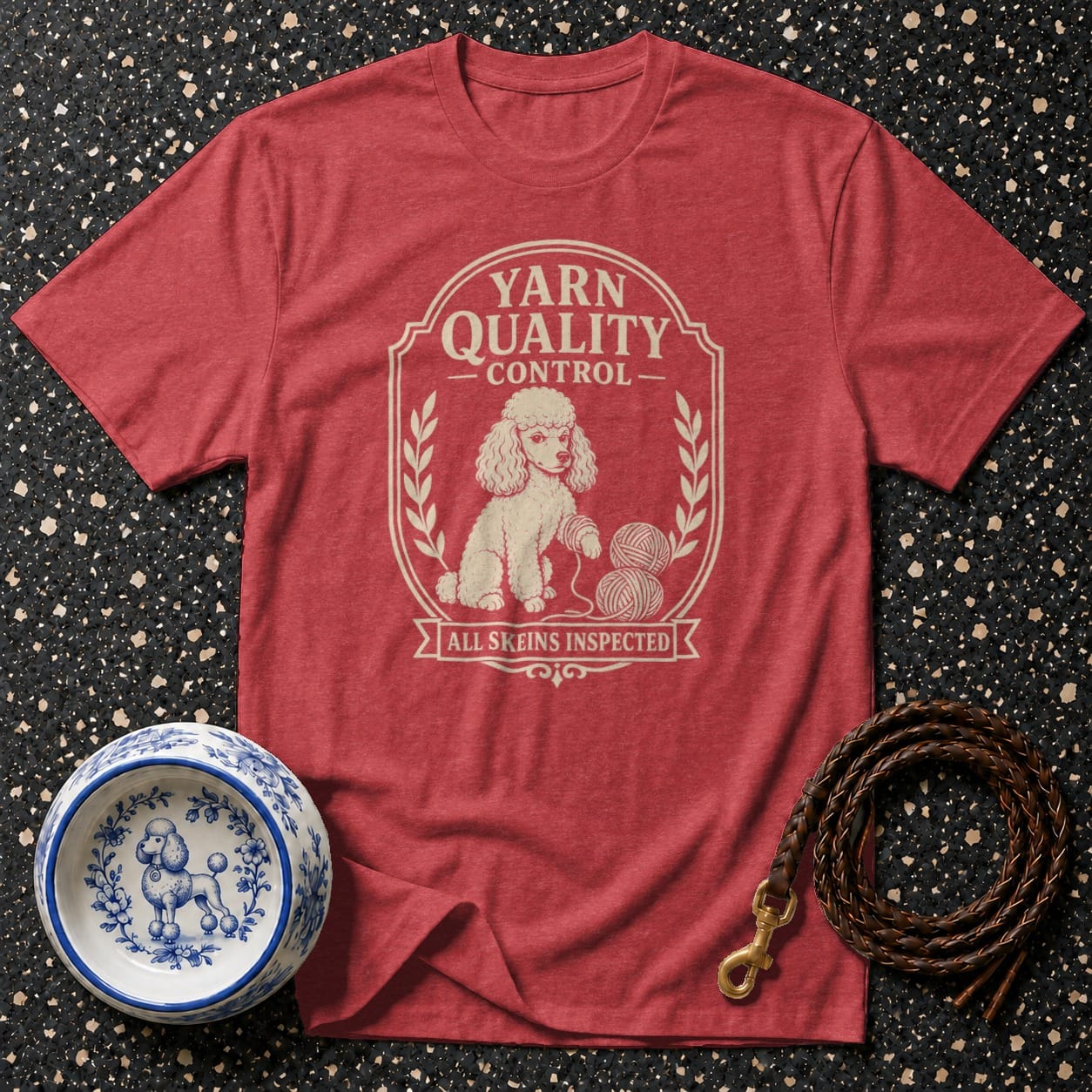 Red t-shirt with a cream graphic of a poodle, yarn, and text reading "Yarn Quality Control".