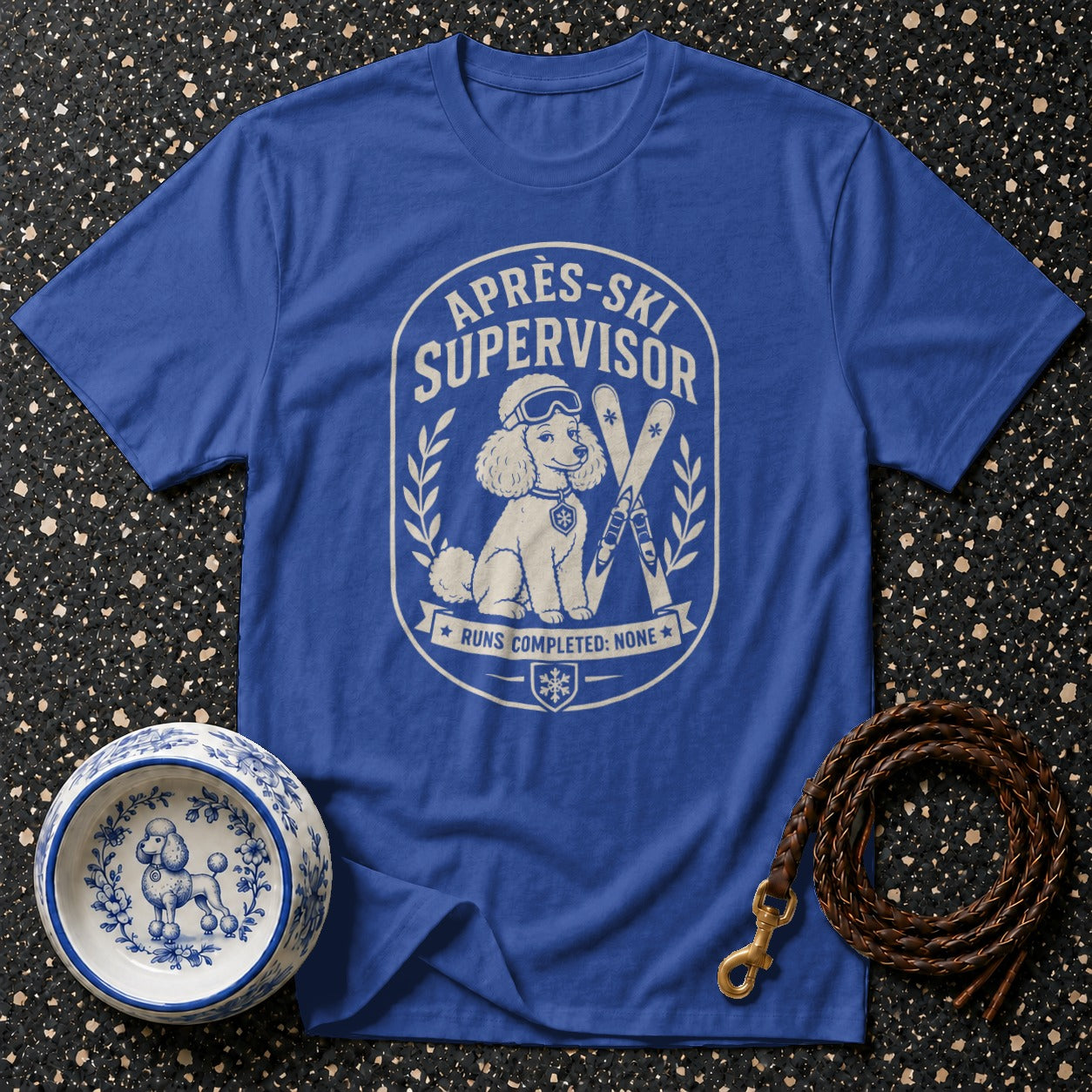 Blue t-shirt with "Après-Ski Supervisor" graphic of a poodle and skis.