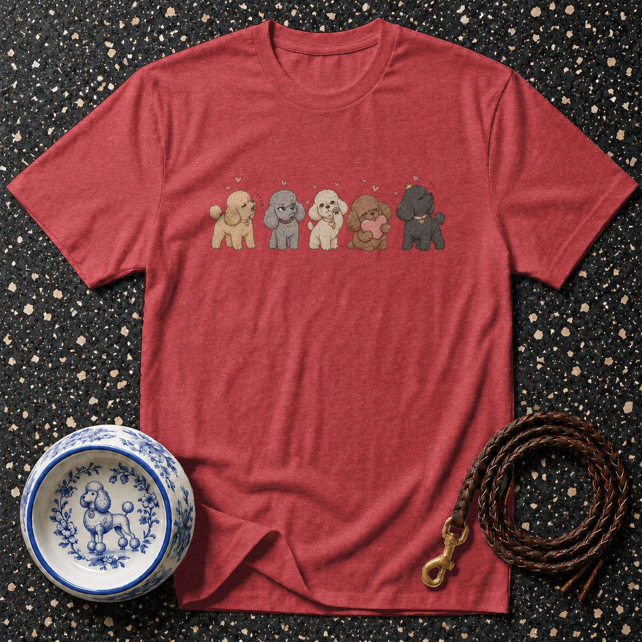 Red t-shirt with five cartoon poodles in different colors and a braided leash with a metal clasp.