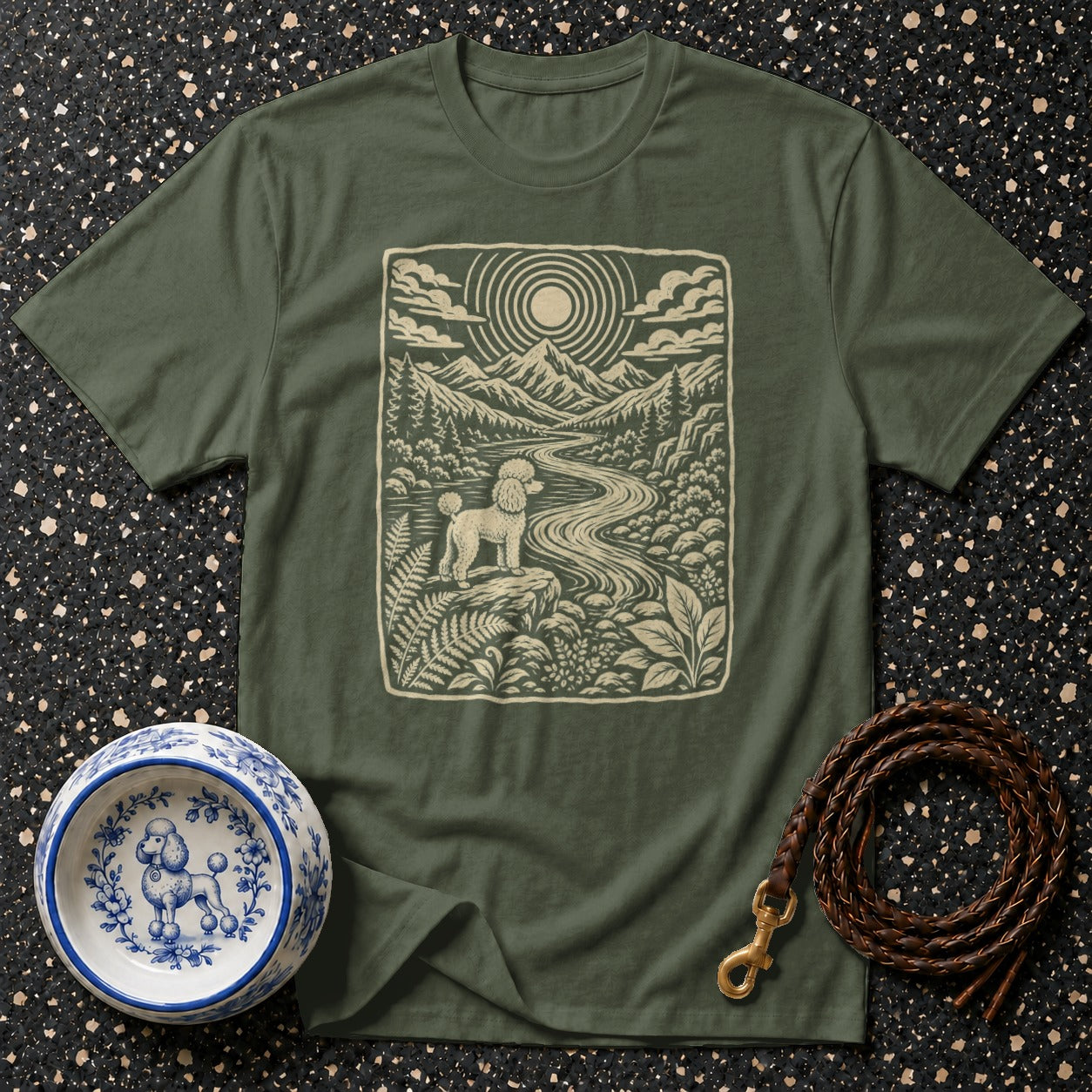 Olive green t-shirt with a vintage outdoor scene featuring a poodle, mountains, and a winding river.