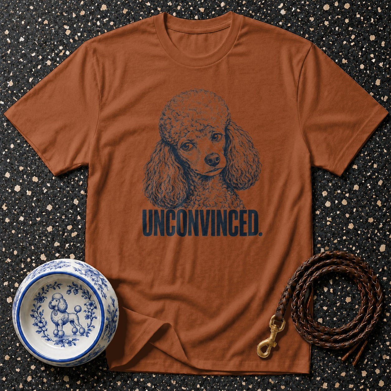 Brown t-shirt with a navy poodle graphic and "UNCONVINCED." text.