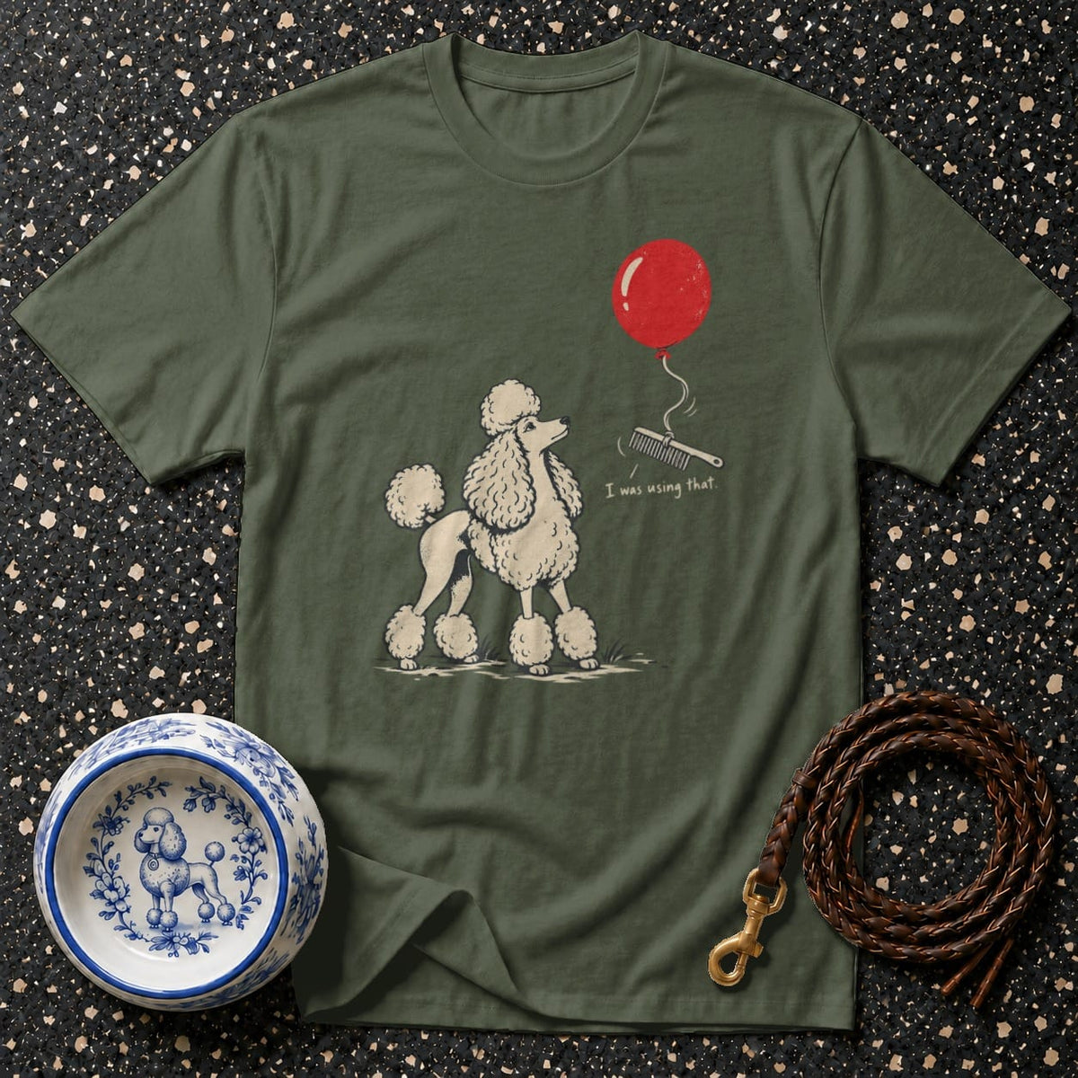 Green t-shirt with poodle, balloon, comb, and text "I was using that".