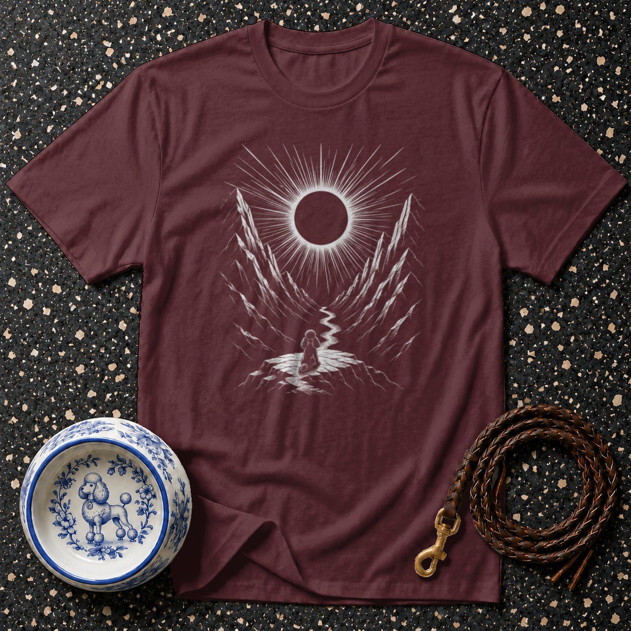 Maroon t-shirt with a white eclipse graphic over a mountain landscape and a winding path.