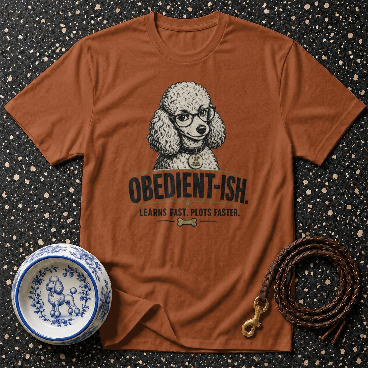 Brown t-shirt with poodle wearing glasses, reads "Obedient-ish. Learns fast. Plots faster."