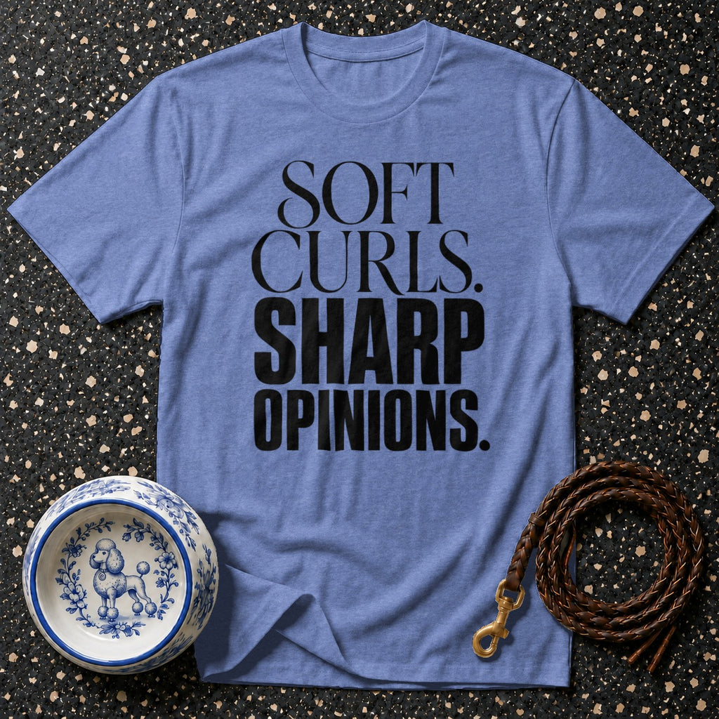 Blue t-shirt with text "SOFT CURLS. SHARP OPINIONS." next to a dog bowl and leash.