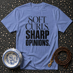 Blue t-shirt with text "SOFT CURLS. SHARP OPINIONS." next to a dog bowl and leash.