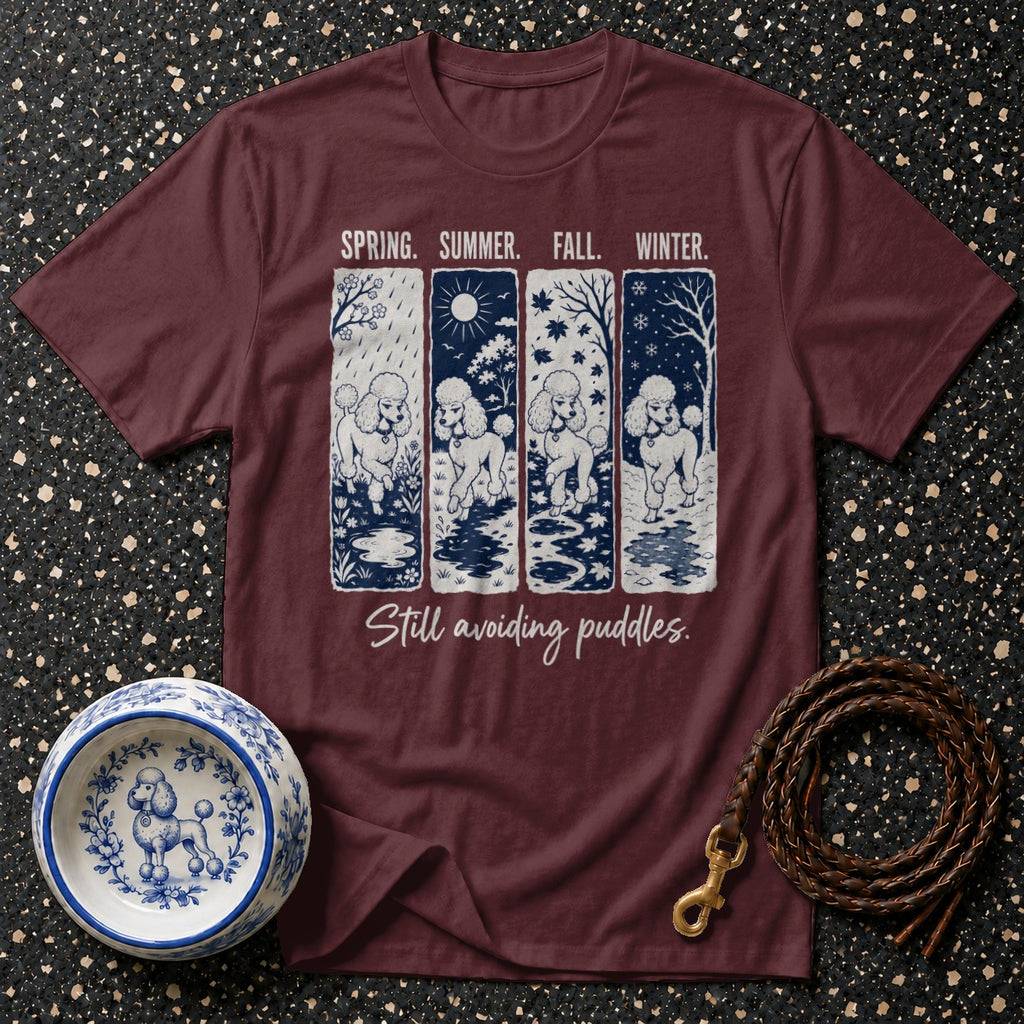 Maroon t-shirt with four panels of poodles in different seasons and text "Still avoiding puddles".