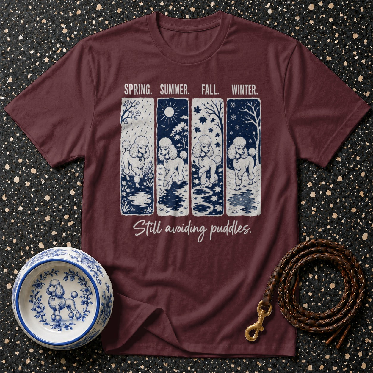 Maroon t-shirt with four panels of poodles in different seasons and text "Still avoiding puddles".