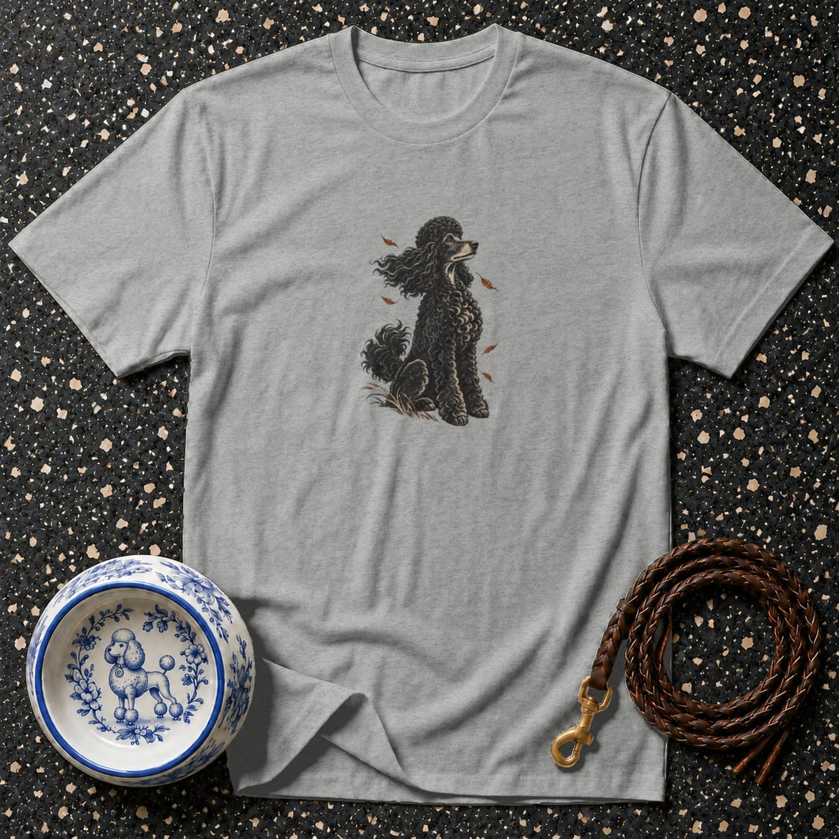 Grey t-shirt with black poodle illustration, decorative dog bowl, and leather leash.