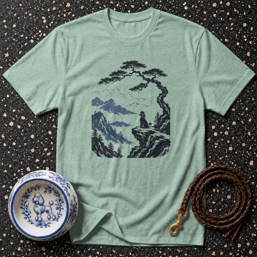 Light green t-shirt with graphic of poodle on cliff under pine tree and mountains.