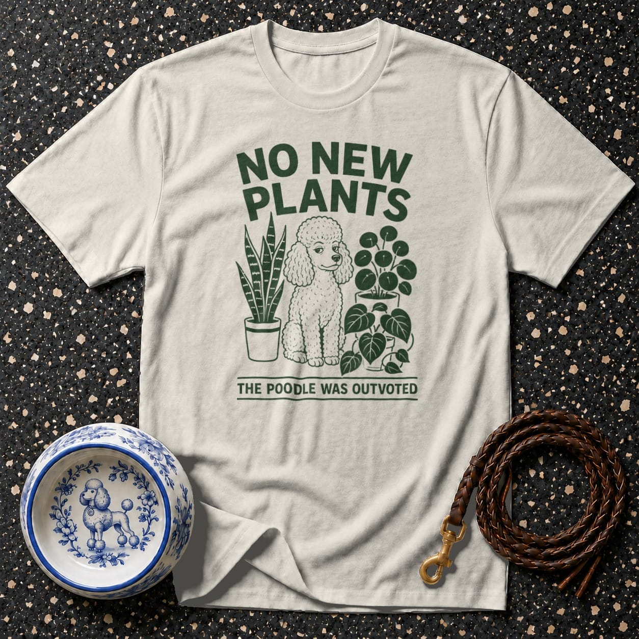 Cream t-shirt with green graphic of a poodle, plants, and text "NO NEW PLANTS THE POODLE WAS OUTVOTED".