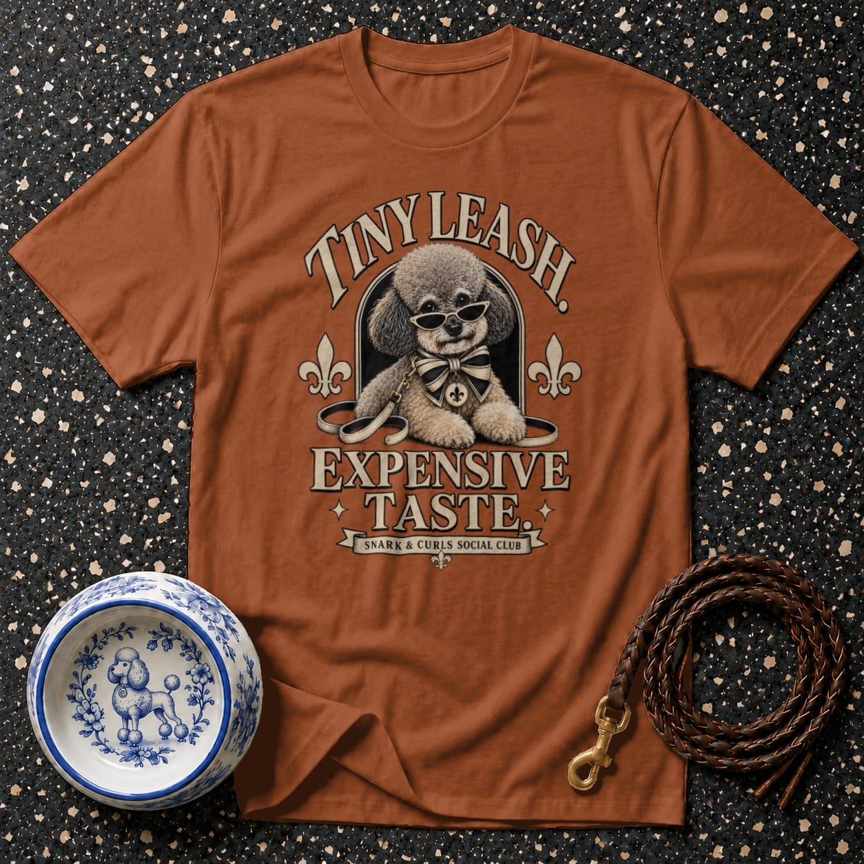 Brown t-shirt with graphic of poodle wearing sunglasses and bow tie, text "TINY LEASH EXPENSIVE TASTE".
