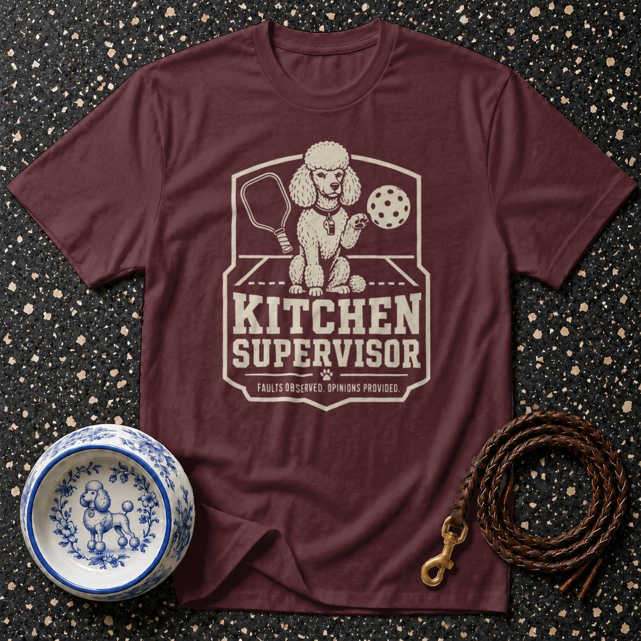 Maroon t-shirt with graphic of a poodle holding a pickleball paddle and ball.