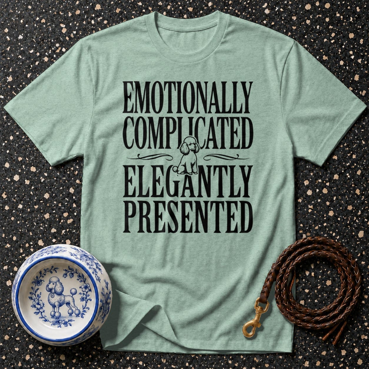 Light green t-shirt with black text "Emotionally Complicated Elegantly Presented" and poodle illustration.