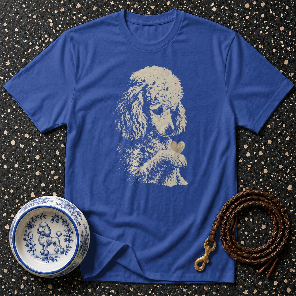 A royal blue t-shirt with a poodle and heart graphic, next to a patterned dog bowl and leash.