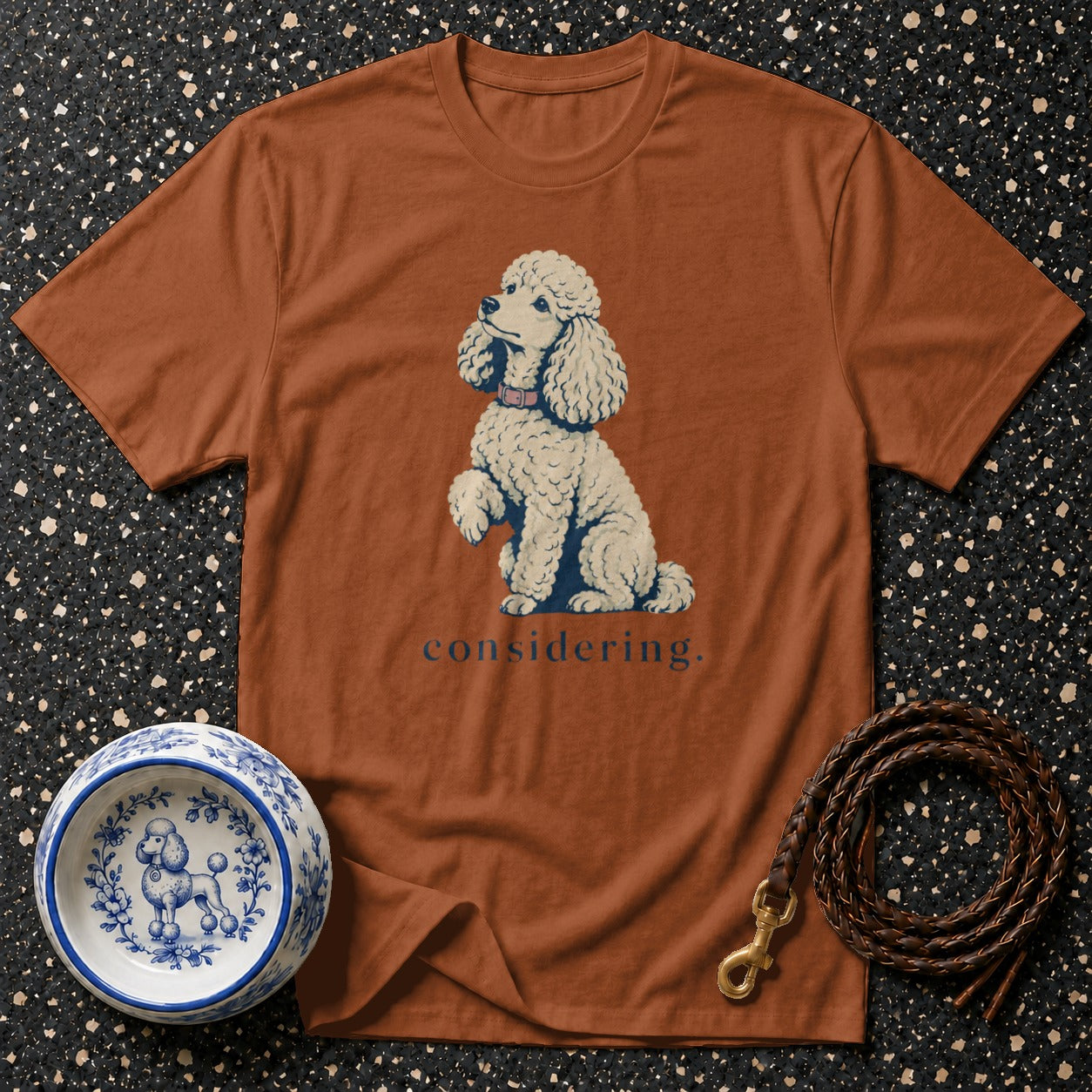 Brown t-shirt with a white poodle illustration and the word "considering."
