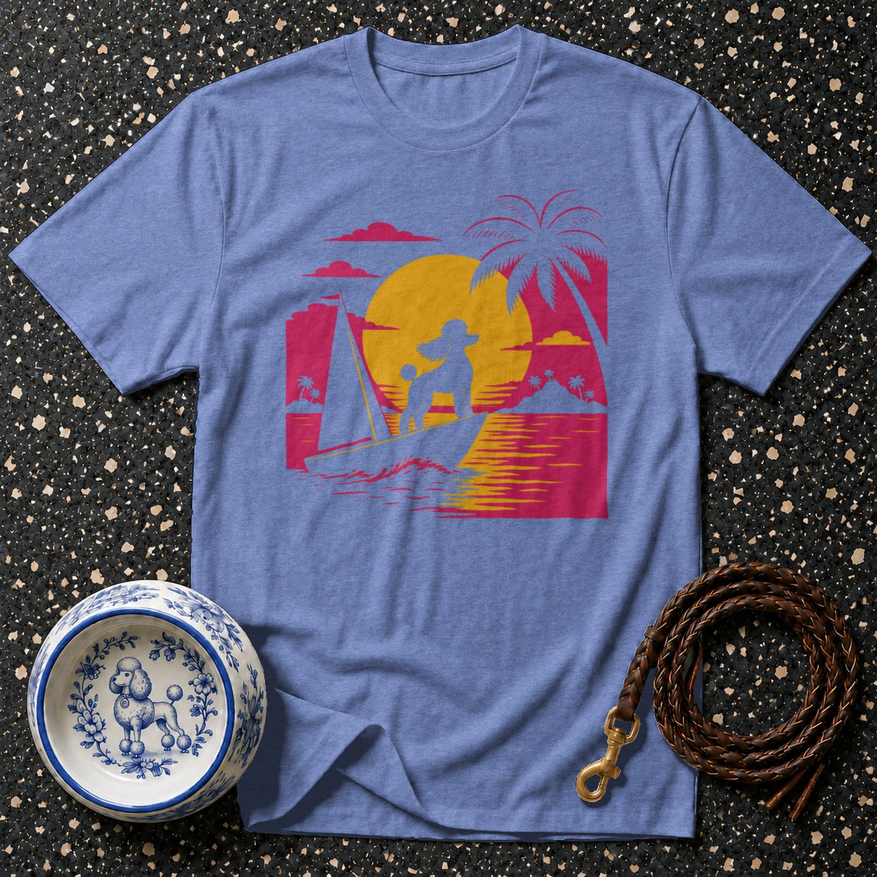 Blue t-shirt with poodle surfing graphic and tropical sunset design.