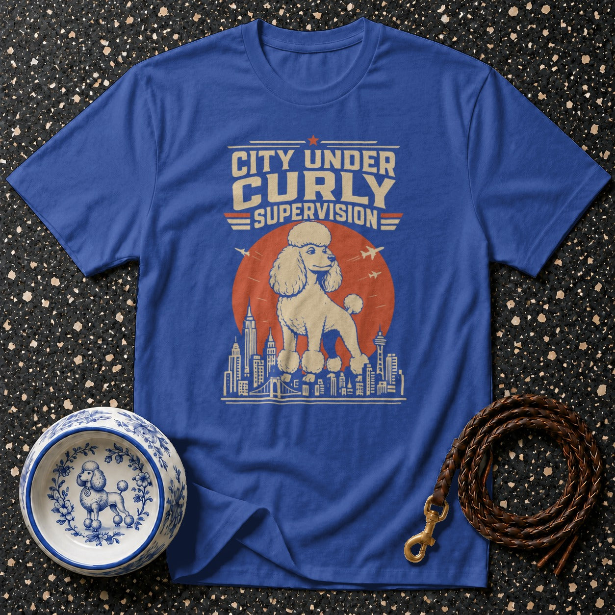 Blue t-shirt with "City Under Curly Supervision" text and poodle illustration.