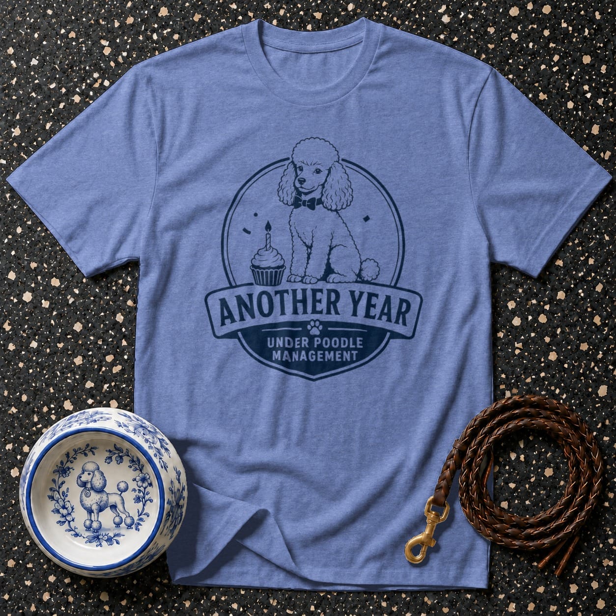 Periwinkle t-shirt with poodle graphic and text "Another Year Under Poodle Management."