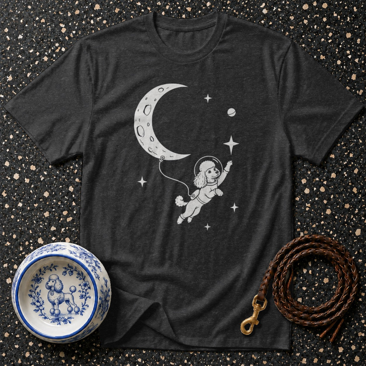 Dark grey t-shirt with a white graphic of a poodle in a spacesuit floating towards the moon.