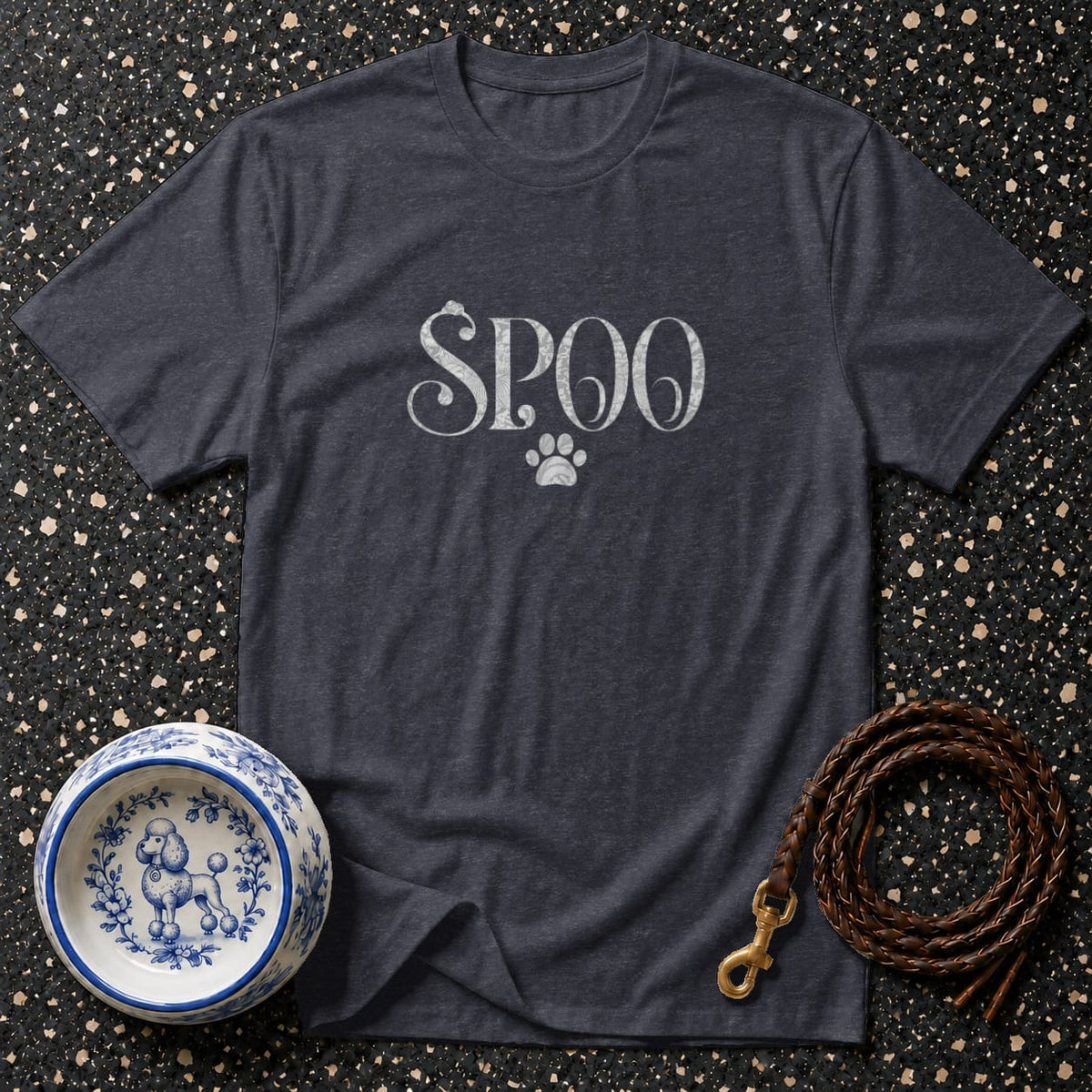 Dark grey t-shirt with "Spoo" and a paw print graphic, next to a dog bowl and leash.