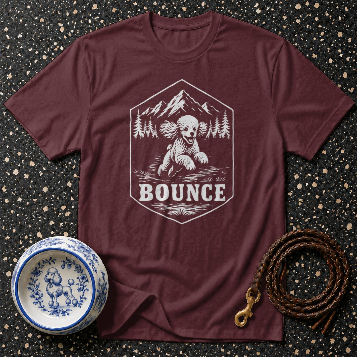 Maroon t-shirt with white hexagon graphic of a running dog and mountains with text "BOUNCE".