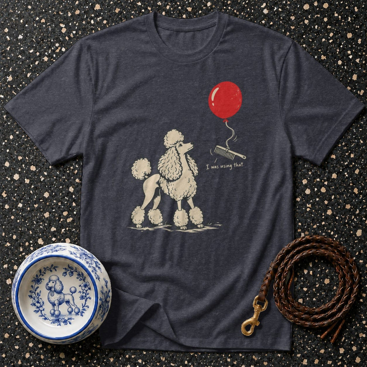 Dark t-shirt with a cream poodle graphic, red balloon, and text "I was using that."