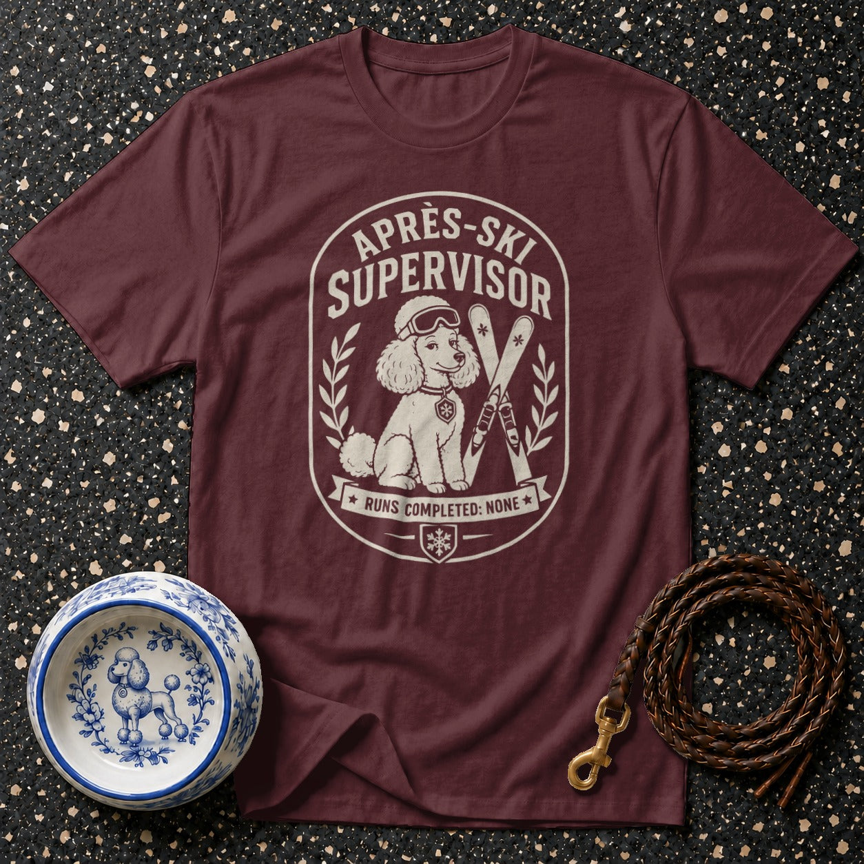 Burgundy t-shirt with "Après-Ski Supervisor" graphic of a poodle with skis.