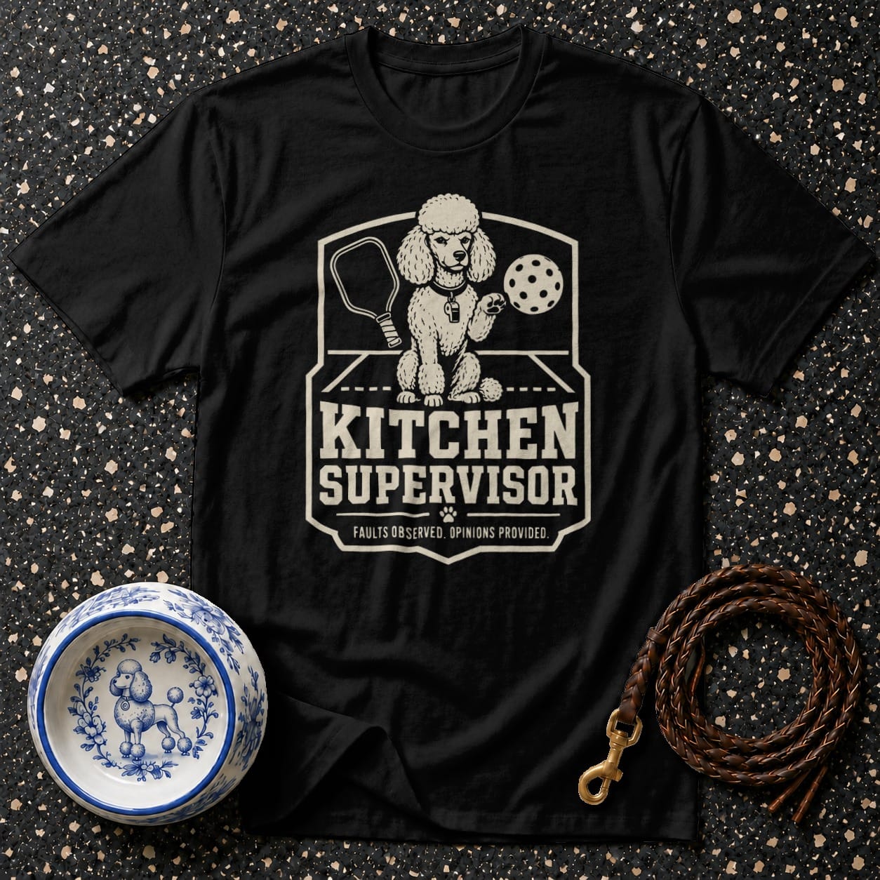Black t-shirt with a graphic of a poodle holding a pickleball paddle and ball.