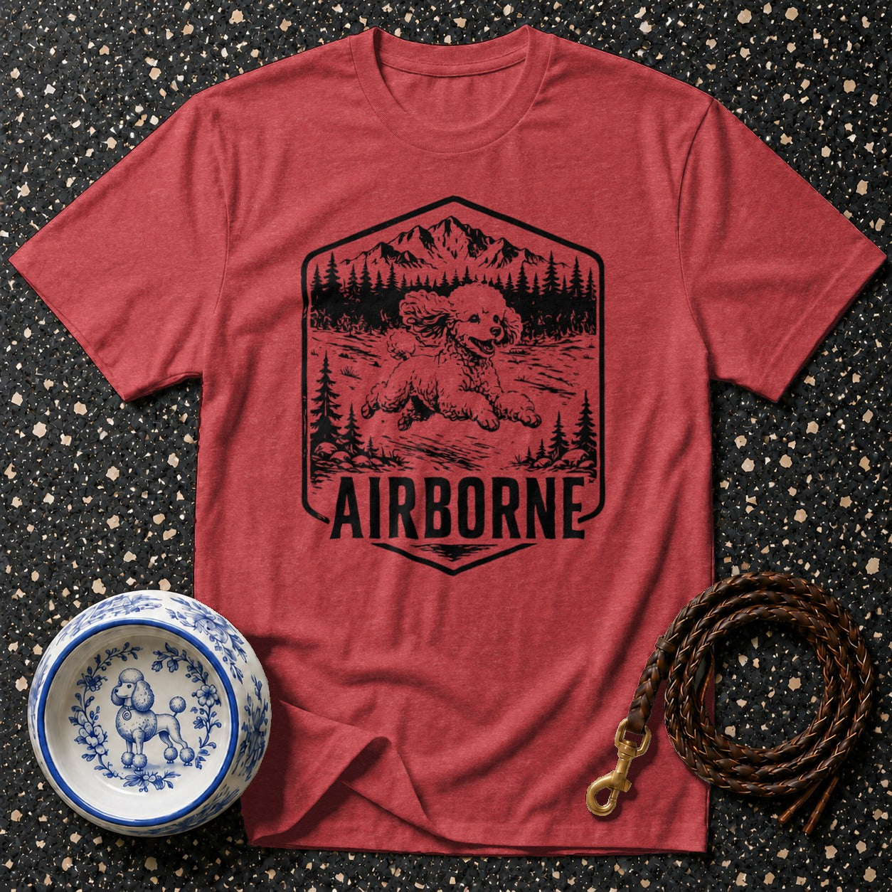 Red t-shirt with a black graphic of a poodle in a mountainous forest scene.