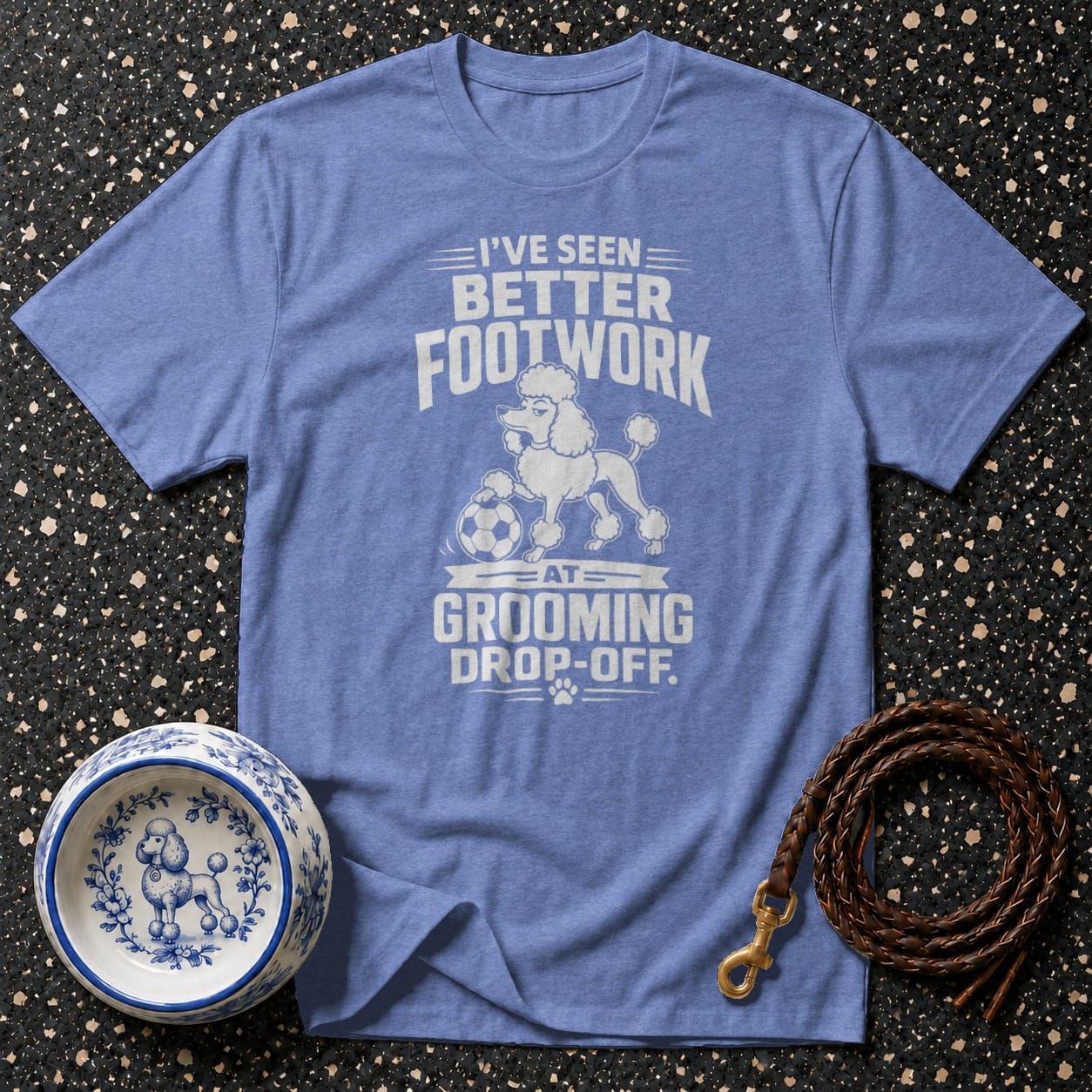 Blue t-shirt with white text and graphic of a poodle playing soccer.