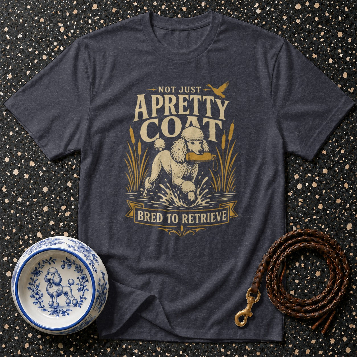 Dark t-shirt with graphic of a poodle retrieving, reading "Not Just A Pretty Coat Bred to Retrieve."