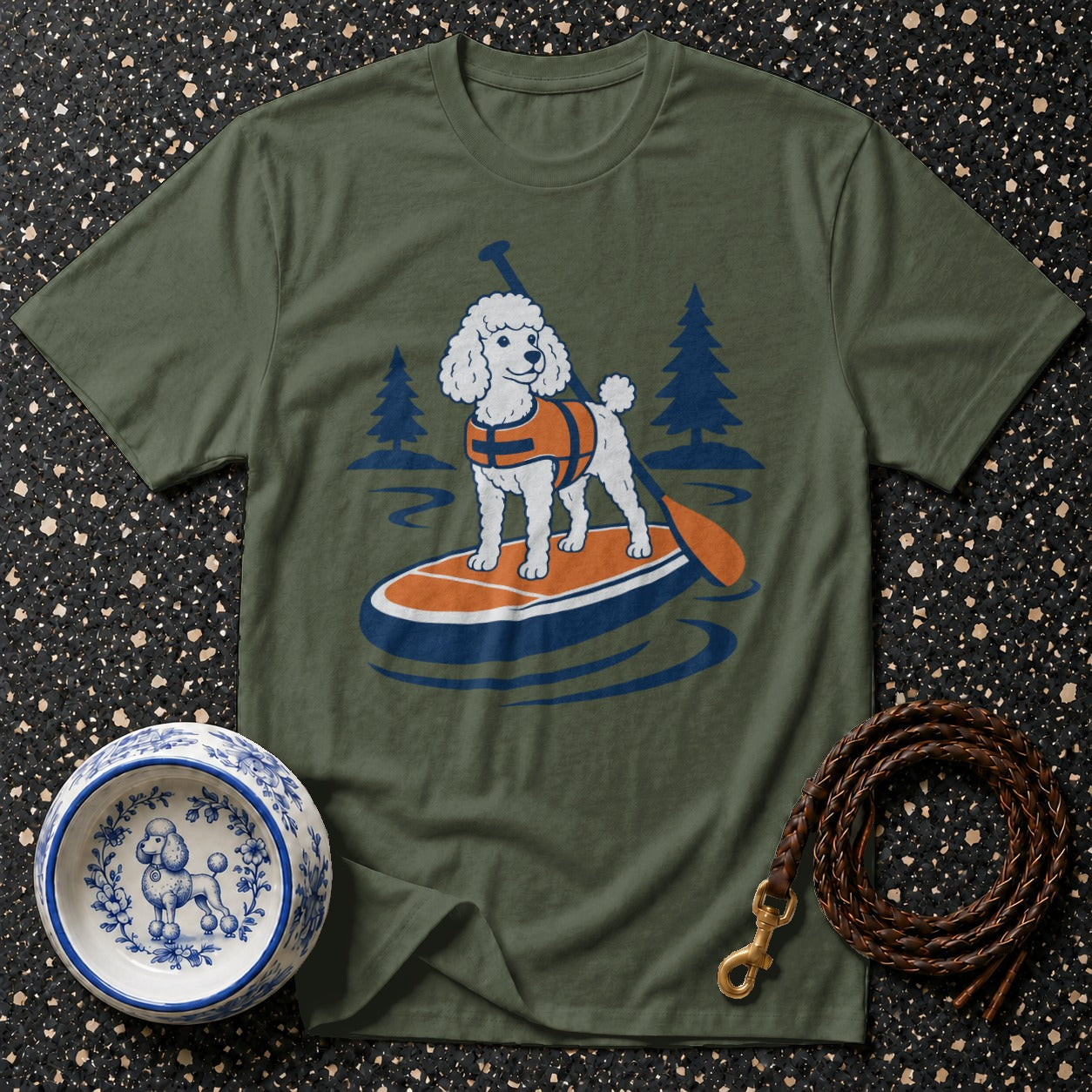 Green t-shirt with graphic of a white poodle on a paddleboard wearing a life vest.