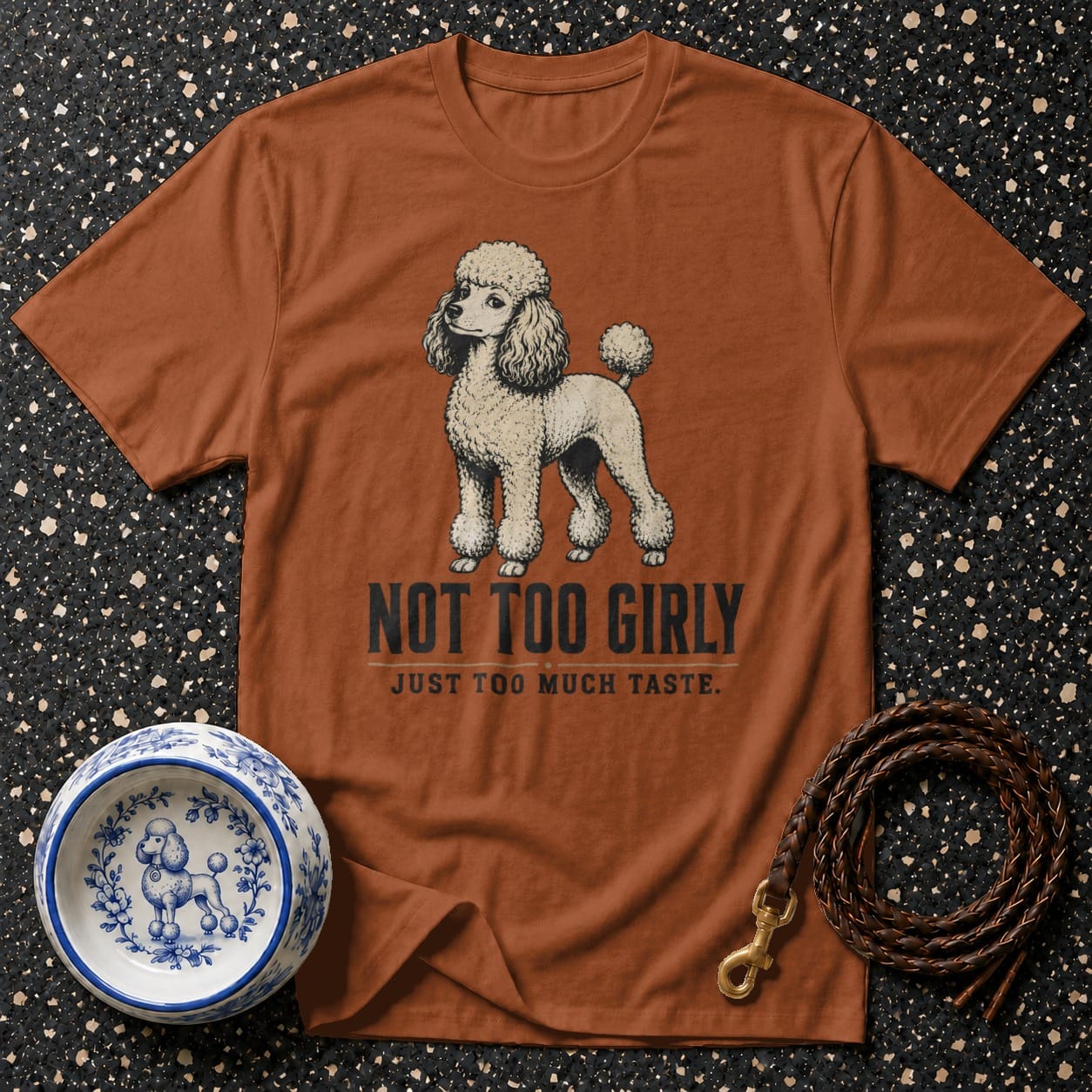 Brown t-shirt with a poodle illustration and text "NOT TOO GIRLY".