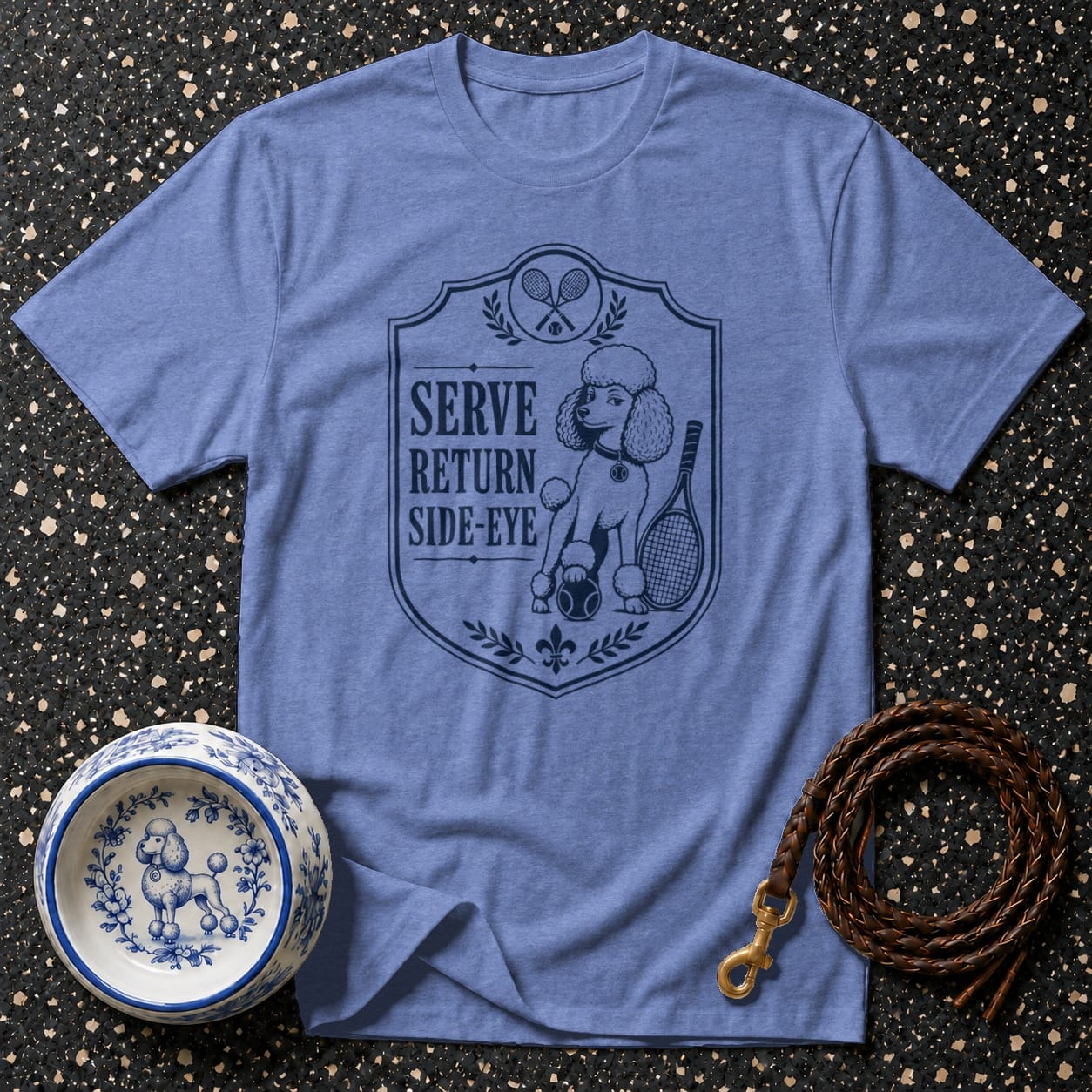 Blue t-shirt with a crest featuring a poodle, tennis rackets, and "SERVE RETURN SIDE-EYE" text.
