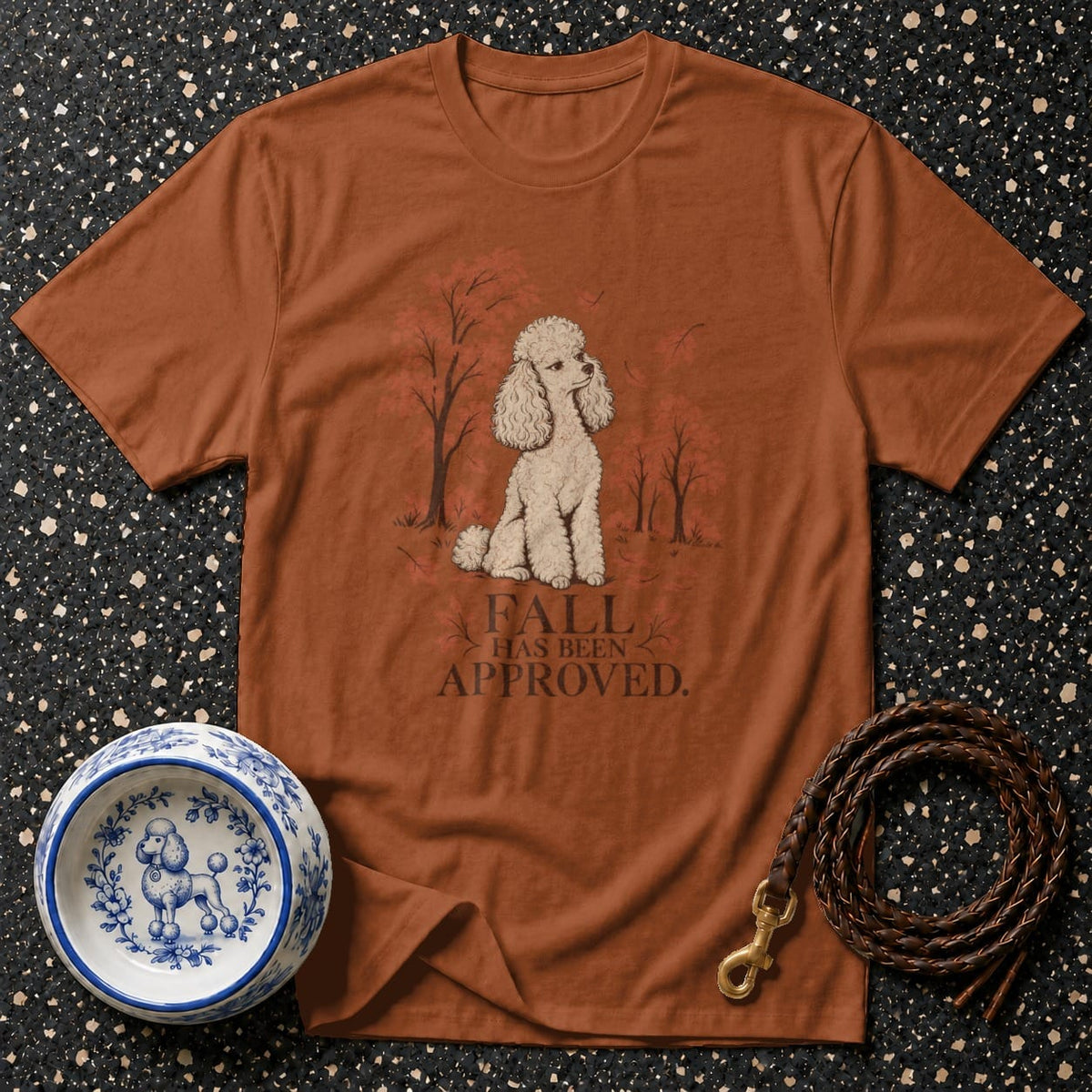 Brown t-shirt with poodle illustration and text "FALL HAS BEEN APPROVED".