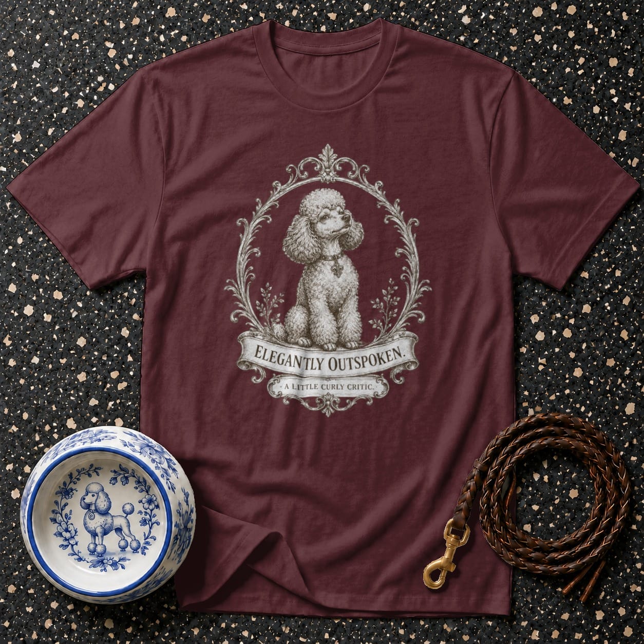 Maroon t-shirt with a poodle illustration and "Elegantly Outspoken." text.