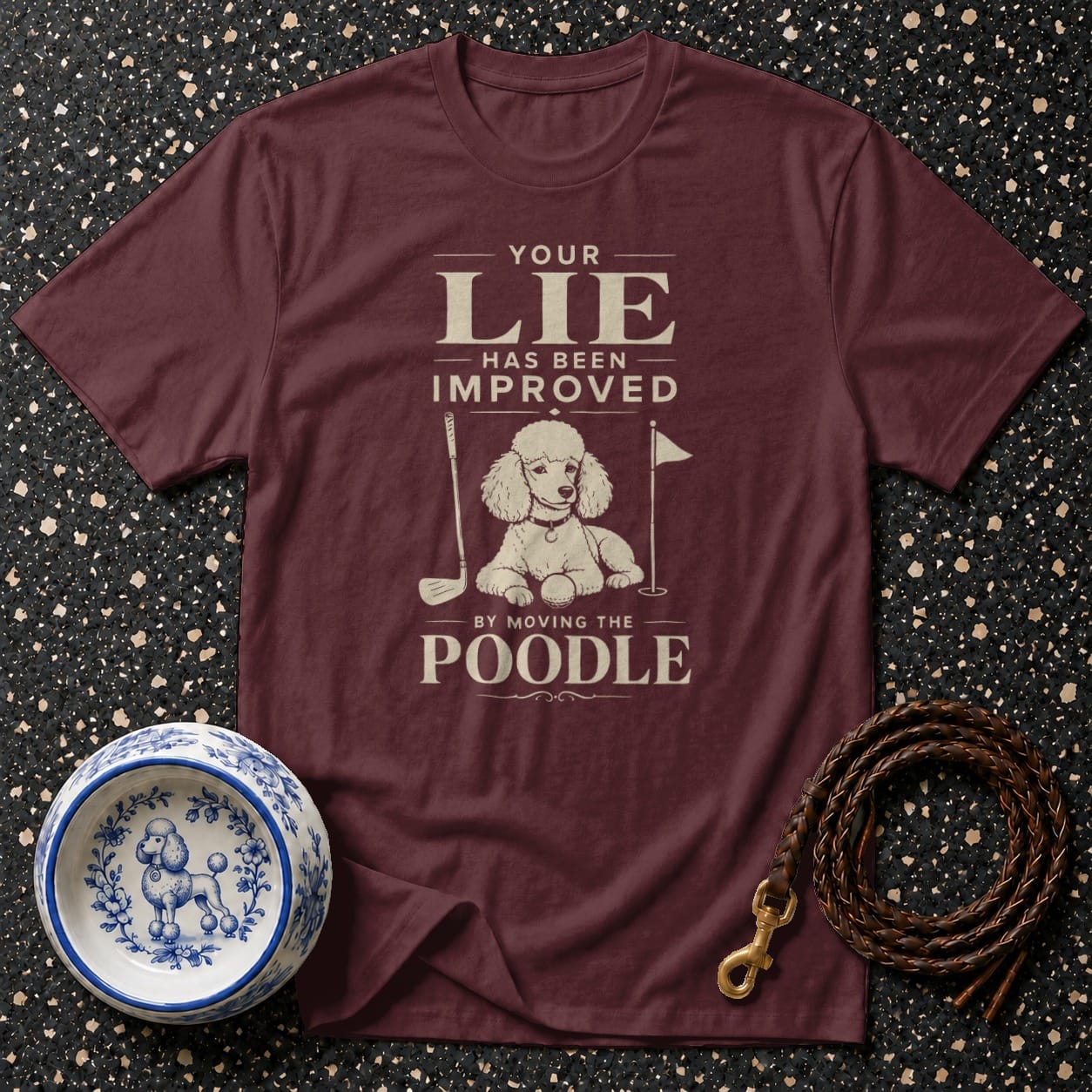 Maroon t-shirt with "Your lie has been improved by moving the poodle" text and poodle graphic.