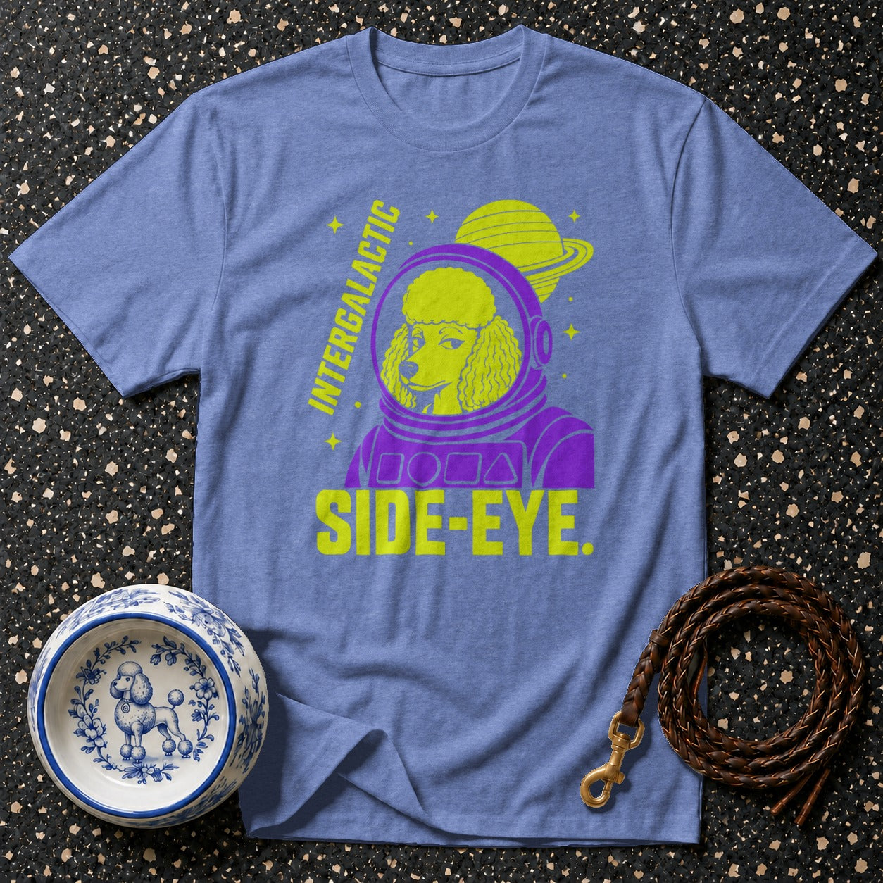 Purple and yellow poodle astronaut graphic on a blue t-shirt with "INTERGALACTIC SIDE-EYE".
