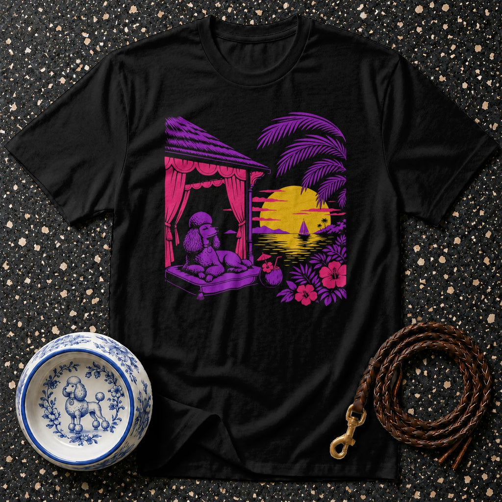 Black t-shirt with a poodle lounging on a cabana bed with a tropical sunset scene.